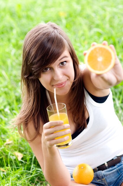 Junge Frau, die Orangen- und Vitamincocktail hält