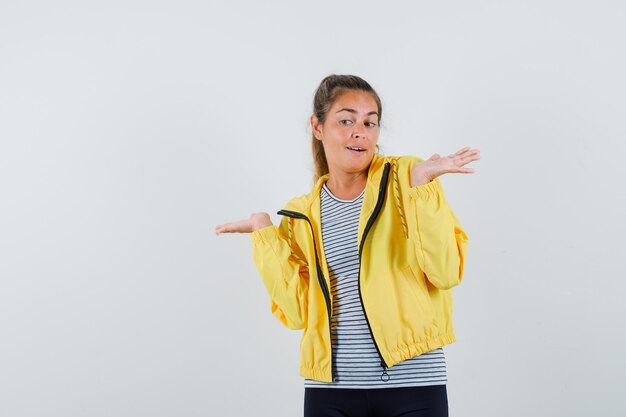 Junge Frau, die Palmen beiseite in T-Shirt, Jacke und schön aussehend ausbreitet. Vorderansicht.