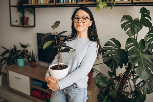Junge Frau, die Pflanzen zu Hause kultiviert