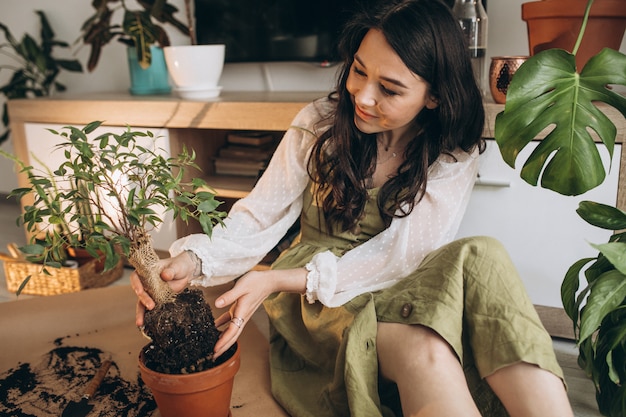 Junge Frau, die Pflanzen zu Hause kultiviert