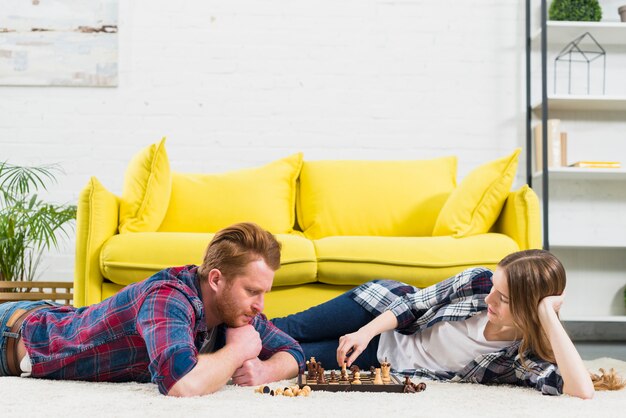 Junge Frau, die Schachspiel mit ihrem Freund spielt