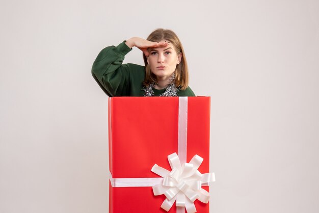 junge Frau, die sich in Geschenkbox auf Weiß versteckt