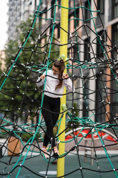 Kostenloses Foto junge frau, die spaß auf der seilpyramide auf dem spielplatz hat