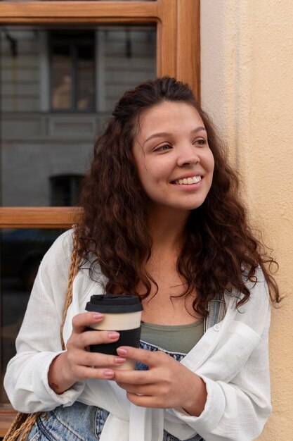 Junge Frau, die Spaß hat, während sie eine Tasse Kaffee hält