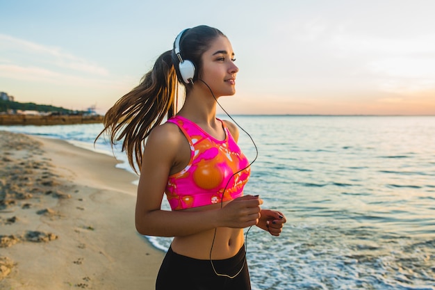 Kostenloses Foto junge frau, die sportübungen am sonnenaufgangstrand am morgen tut