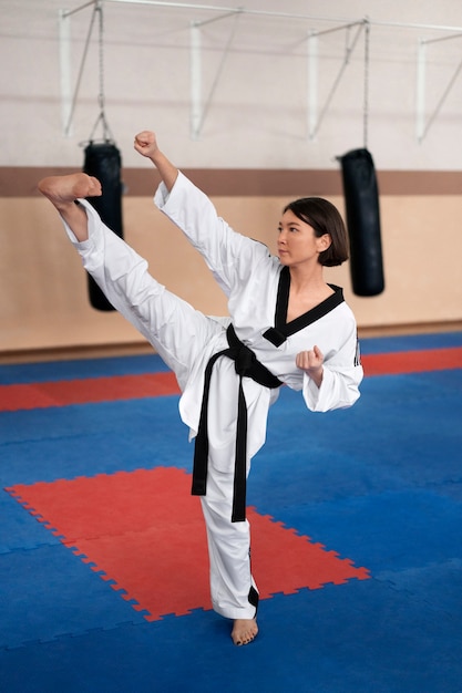 Kostenloses Foto junge frau, die taekwondo in einer turnhalle praktiziert