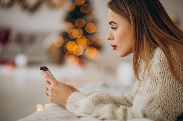 Junge Frau, die Telefon an Weihnachten benutzt