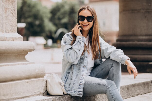 Junge Frau, die Telefon außerhalb der Stadt benutzt