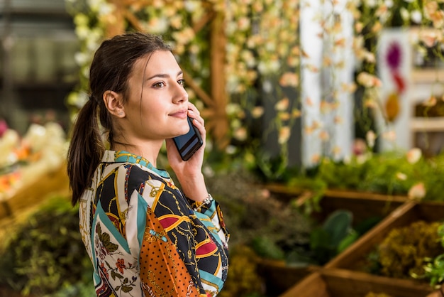 Junge Frau, die telefonisch im grünen Haus spricht