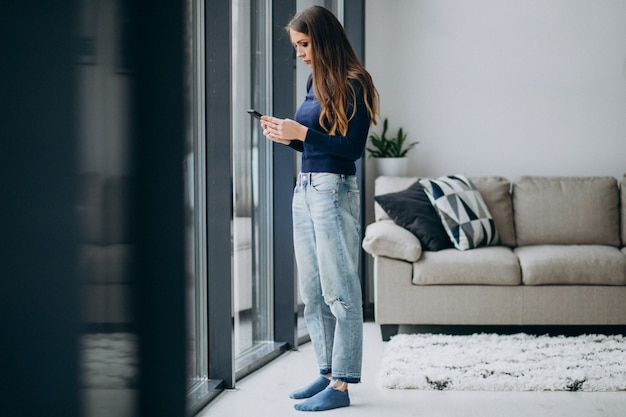 junge Frau, die Telefontastatur durch das Fenster tippt