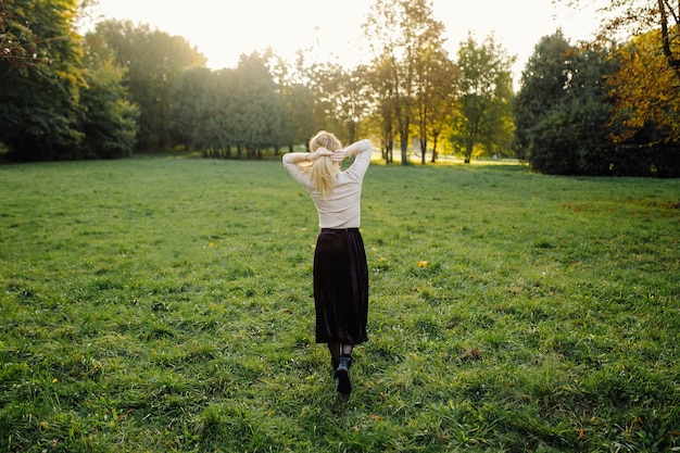 Junge Frau, die über gelben Blättern im Herbst-Park aufwirft. Draussen