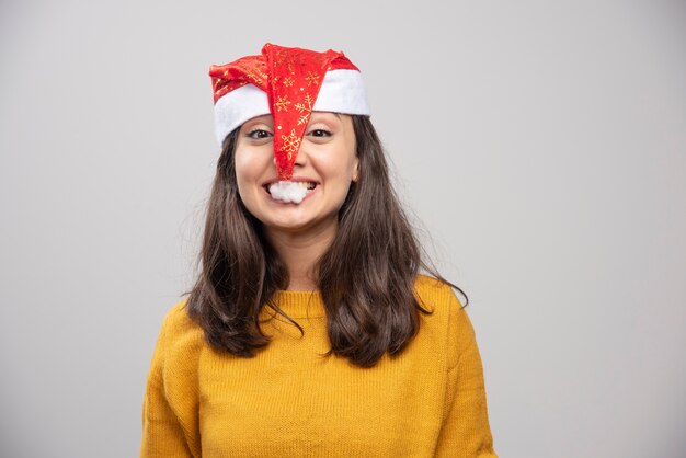 Junge Frau, die versucht, roten Hut des Weihnachtsmanns zu essen.