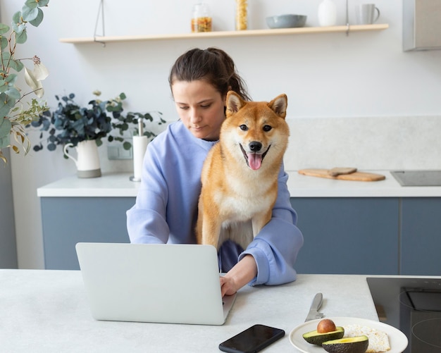 Junge Frau, die versucht zu arbeiten, während ihr Hund sie ablenkt