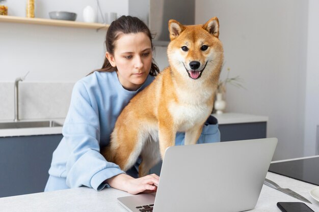 Junge Frau, die versucht zu arbeiten, während ihr Hund sie ablenkt