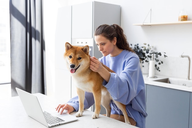 Junge Frau, die versucht zu arbeiten, während ihr Hund sie ablenkt