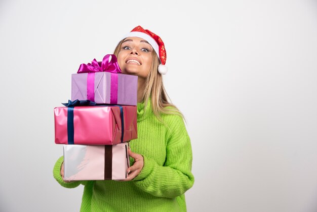 Junge Frau, die viele festliche Weihnachtsgeschenke hält.