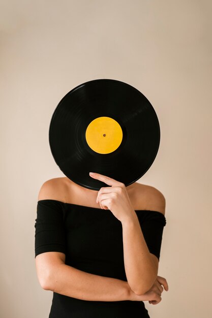 Junge Frau, die Vinylaufzeichnung über ihrem Gesicht hält