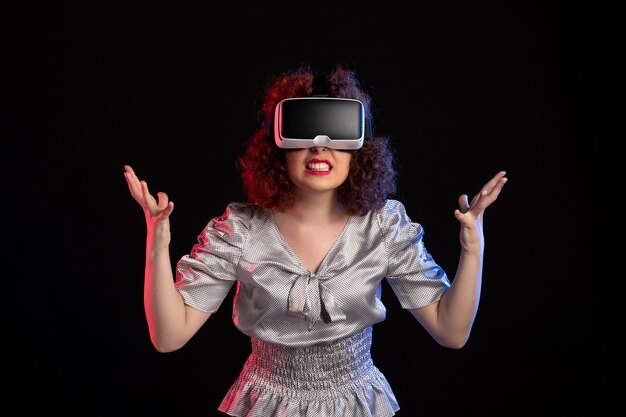 Junge Frau, die Virtual-Reality-Headset auf dunkler Oberfläche trägt