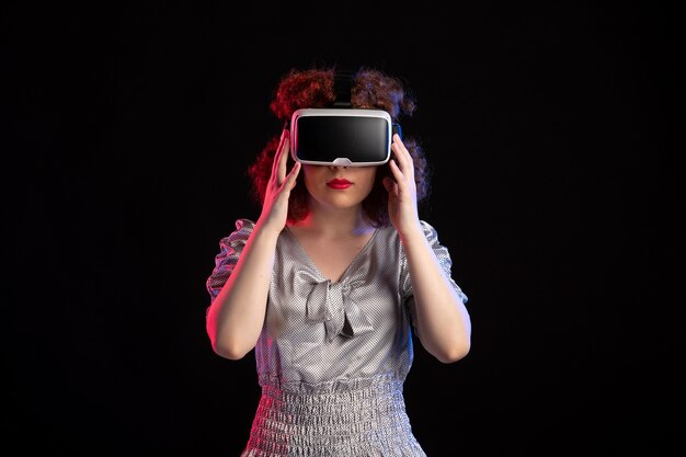 Junge Frau, die Virtual-Reality-Headset auf dunkler Oberfläche trägt