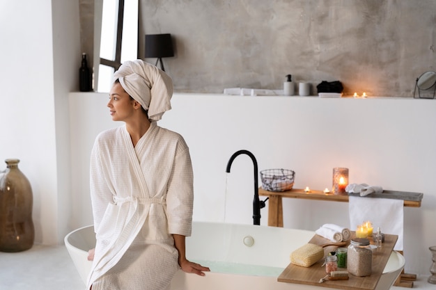 Kostenloses Foto junge frau, die vor dem baden an der badewanne sitzt