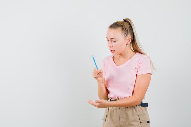 Junge Frau, die vorgibt, auf ihrer Handfläche in T-Shirt, Hose, Vorderansicht zu schreiben.