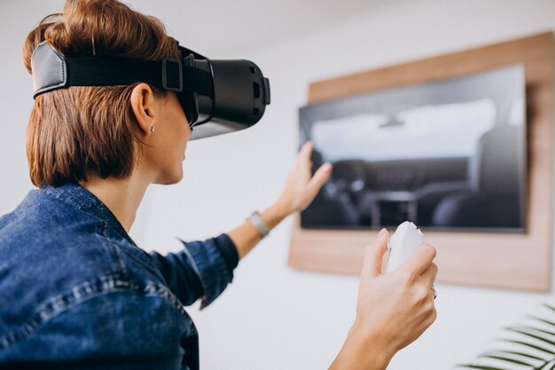 Junge Frau, die VR-Gläser trägt und virtuelles Spiel unter Verwendung der Direktübertragung spielt