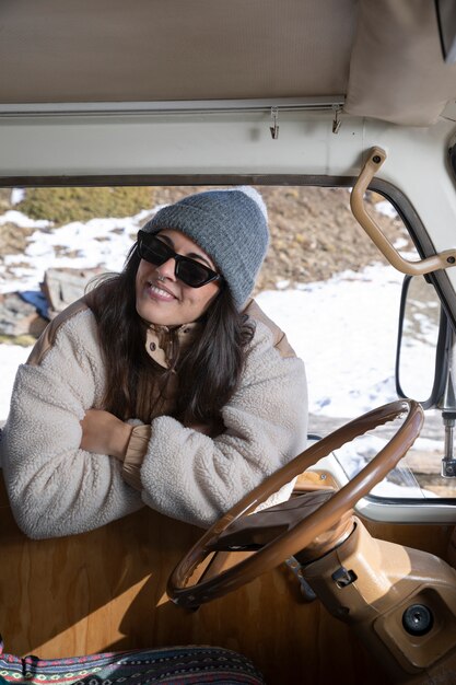 Junge Frau, die während der Winterreise vor dem Wohnmobil steht