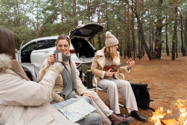 Kostenloses Foto junge frau, die während des camps banjo für ihre freunde spielt