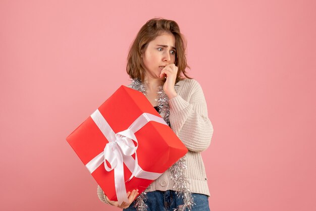 junge Frau, die Weihnachten in ihren Händen auf Rosa hält