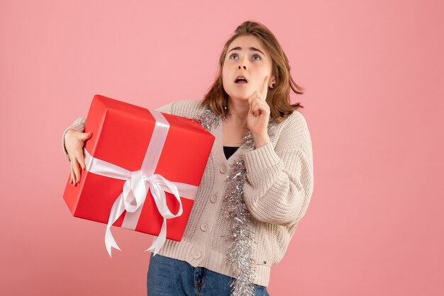 junge Frau, die Weihnachten in ihren Händen auf Rosa hält