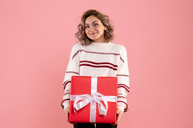 Kostenloses Foto junge frau, die weihnachtsgeschenk auf rosa hält