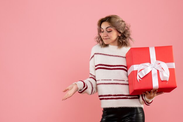 junge Frau, die Weihnachtsgeschenk auf rosa hält