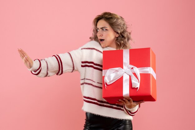 junge Frau, die Weihnachtsgeschenk auf rosa hält