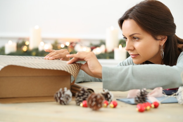 Kostenloses Foto junge frau, die weihnachtsgeschenk einwickelt