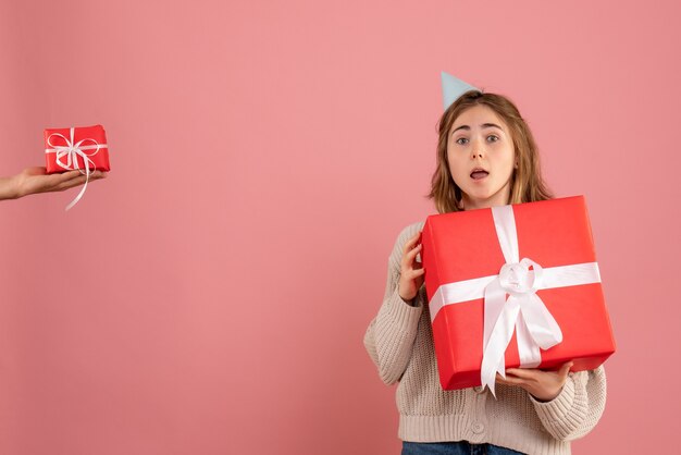 junge Frau, die Weihnachtsgeschenk hält und Geschenk vom Mann auf rosa annimmt