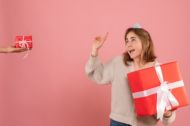 junge Frau, die Weihnachtsgeschenk hält und Geschenk vom Mann auf rosa annimmt