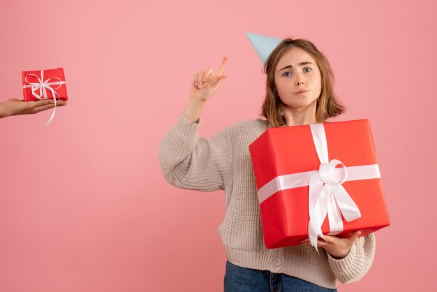 junge Frau, die Weihnachtsgeschenk hält und Geschenk vom Mann auf rosa annimmt