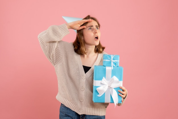 Junge frau, die weihnachtsgeschenke auf rosa hält