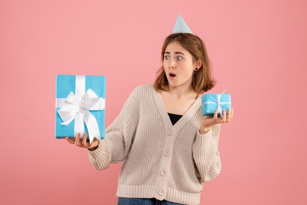 junge Frau, die Weihnachtsgeschenke auf rosa hält