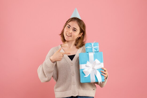 junge Frau, die Weihnachtsgeschenke auf rosa hält