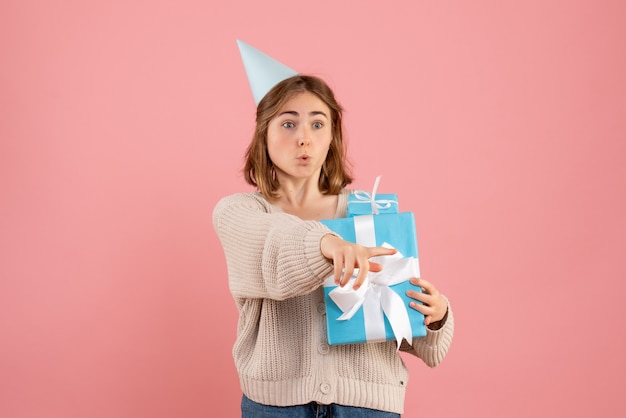 junge Frau, die Weihnachtsgeschenke auf rosa hält