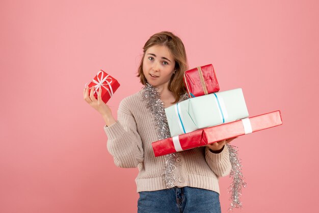 junge Frau, die Weihnachtsgeschenke auf rosa trägt