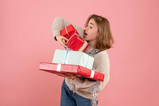 junge Frau, die Weihnachtsgeschenke auf rosa trägt