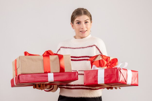 junge Frau, die Weihnachtsgeschenke auf Weiß trägt