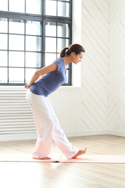 Junge Frau, die Yoga auf einer Yogamatte praktiziert