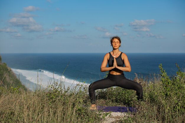 Junge Frau, die Yoga im Freien mit erstaunlicher Rückansicht tut. Bali. Indonesien.