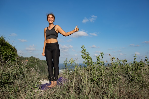 Junge Frau, die Yoga im Freien mit erstaunlicher Rückansicht tut. Bali. Indonesien.