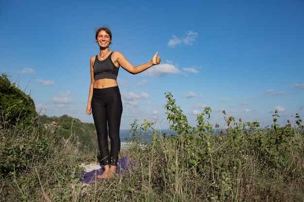 Junge Frau, die Yoga im Freien mit erstaunlicher Rückansicht tut. Bali. Indonesien.