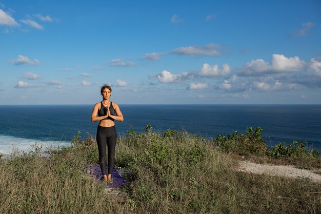 Junge Frau, die Yoga im Freien mit erstaunlicher Rückansicht tut. Bali. Indonesien.