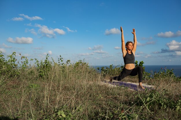 Junge Frau, die Yoga im Freien mit erstaunlicher Rückansicht tut. Bali. Indonesien.